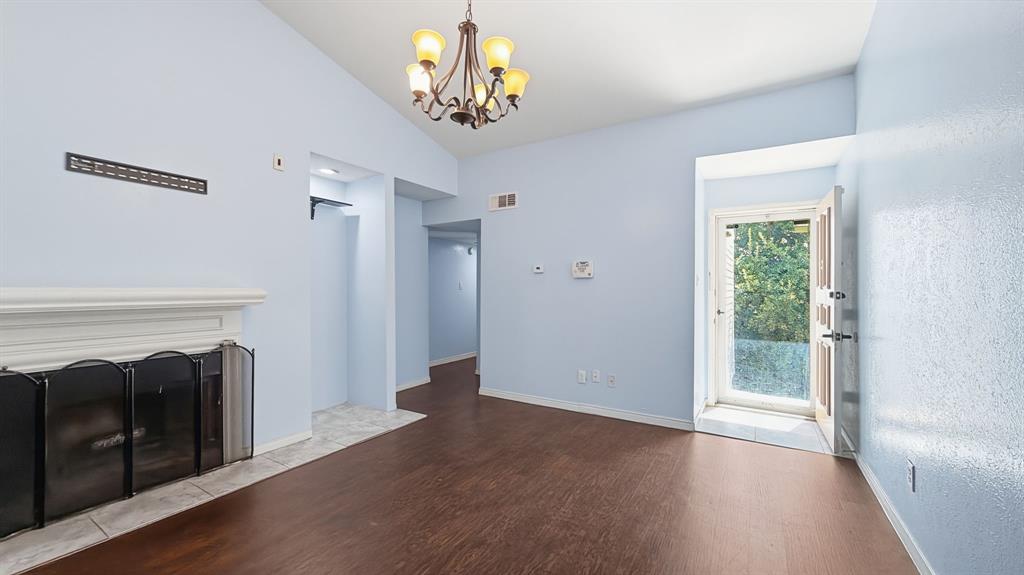12921 Abrams Road, Unit 208 Dallas, TX 75243 - Photo 7 of 19 Vaulted ceiling with an ornate chandelier, wood-finish flooring, and a fireplace with a white mantel and hearth