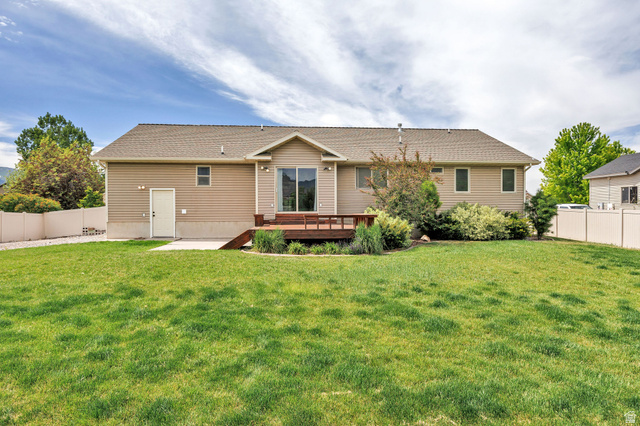 2912 South 1080th Street West Logan, UT 84321 - Photo 40 of 43 Expansive rear yard featuring a large wooden deck, sliding glass door access, vinyl siding, a tan privacy fence, and mature landscaping