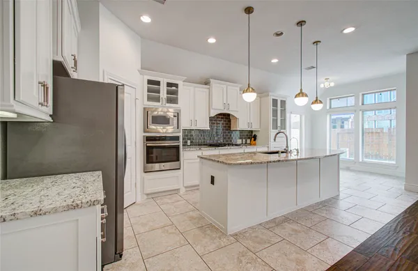 a kitchen with stainless steel appliances granite countertop a sink a stove and a refrigerator