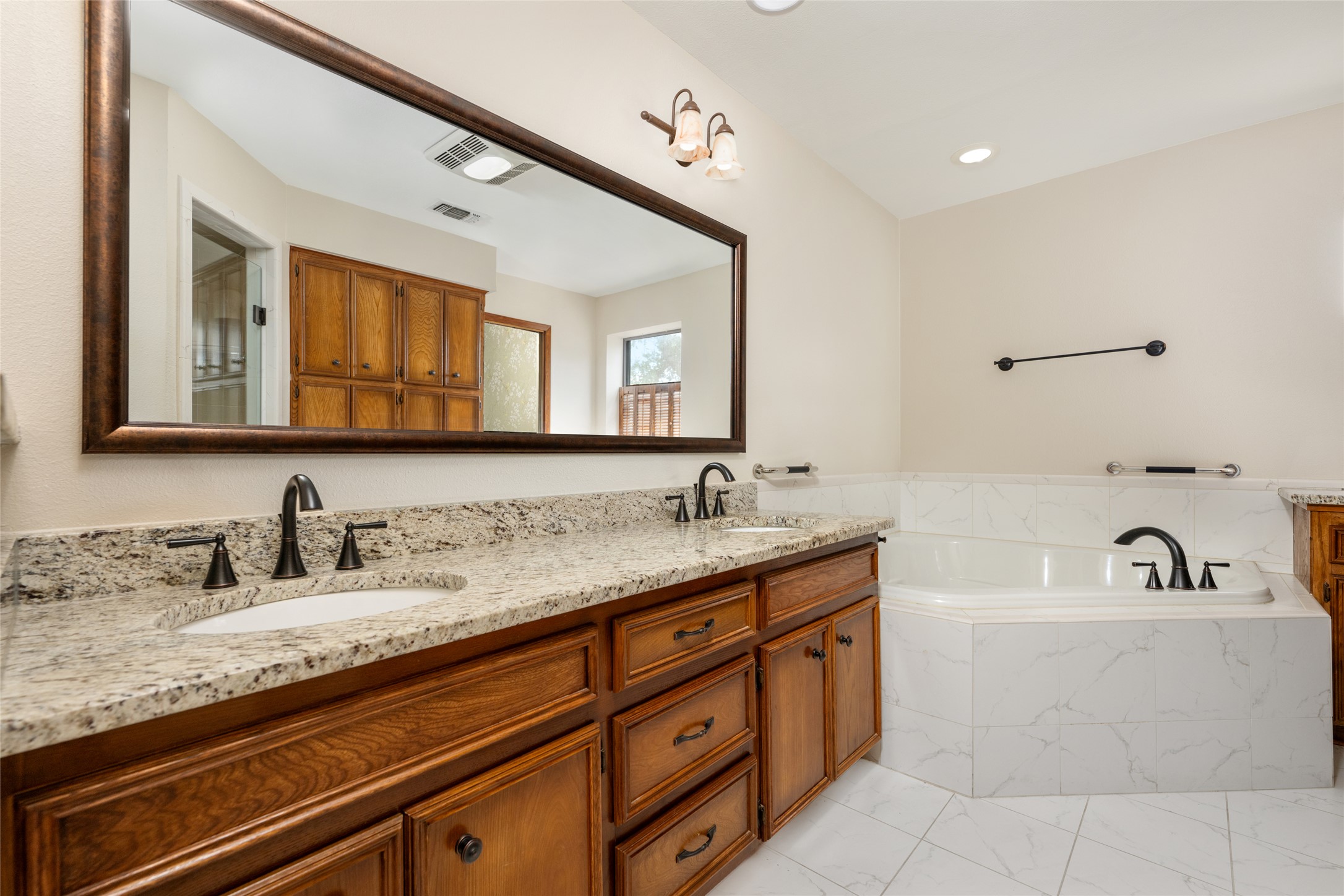 5319 Musket Ridge Austin, TX 78759 - Photo 23 of 39 Dual vanities with granite counters and a luxurious soaking tub define this well-appointed primary bathroom.