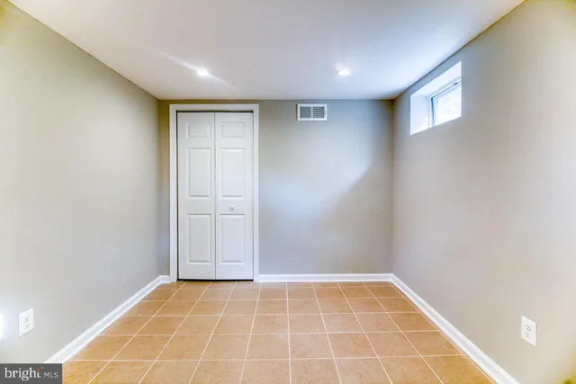 a view of an empty room with closet and wooden floor
