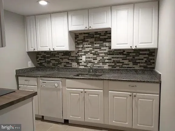a kitchen with granite countertop white cabinets and sink