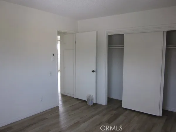 a view of an empty room with wooden floor and closet