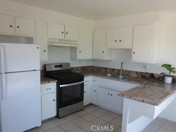 a kitchen with granite countertop a sink stove and white cabinets