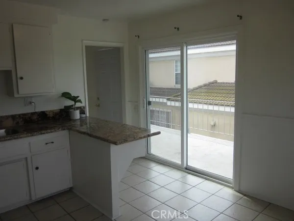 a kitchen with granite countertop a refrigerator and white cabinets