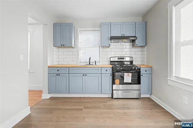 a kitchen with stainless steel appliances a stove and white cabinets