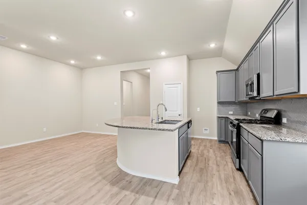a kitchen with stainless steel appliances granite countertop a sink stove and wooden floor