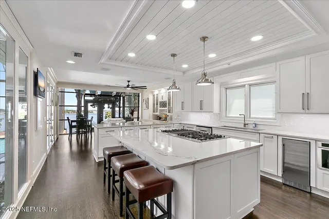 a kitchen with counter top with sink and view living room