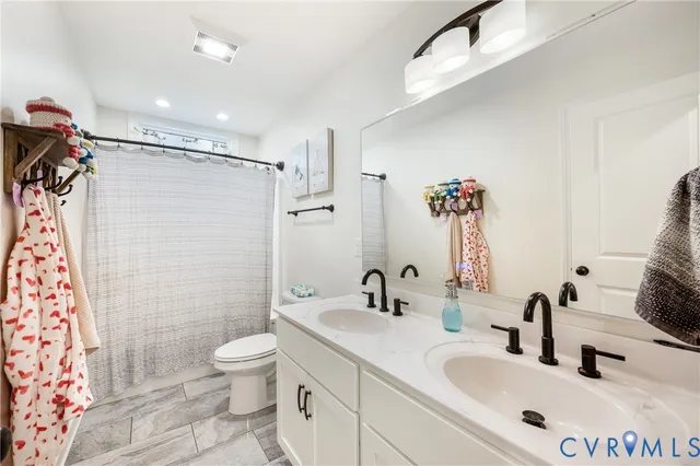 a bathroom with a sink toilet double vanity and shower