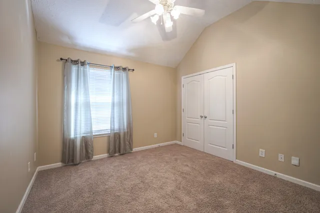 an empty room with windows and chandelier fan