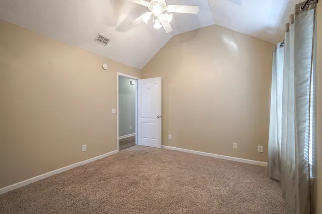 an empty room with a chandelier fan and closet area