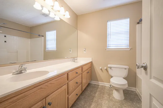 a spacious bathroom with a toilet a sink and mirror