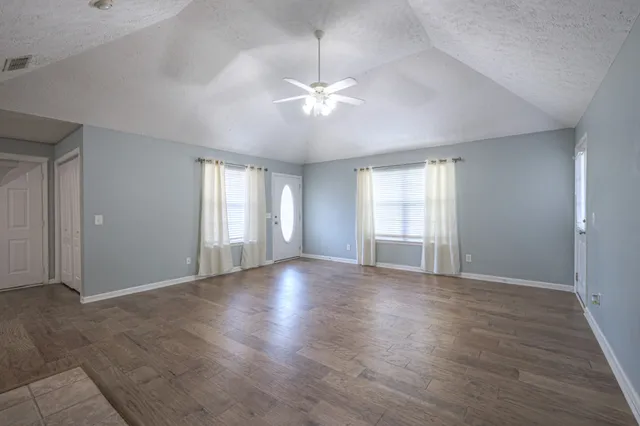 a view of an empty room with window and wooden floor