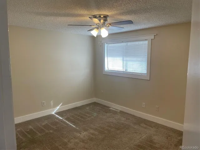 an empty room with a window and a chandelier fan