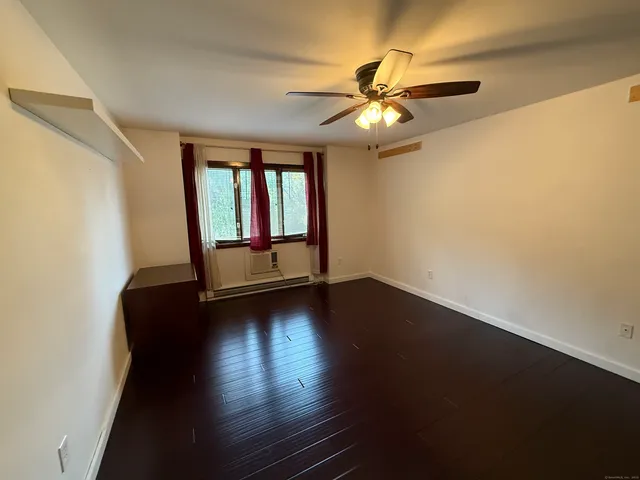 an empty room with wooden floor fan and windows