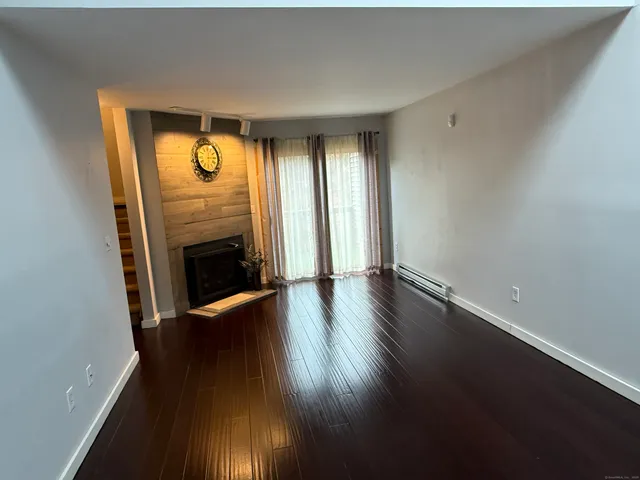 an empty room with wooden floor fireplace and windows