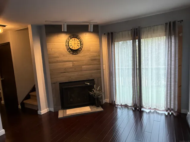 an empty room with wooden floor fireplace and window