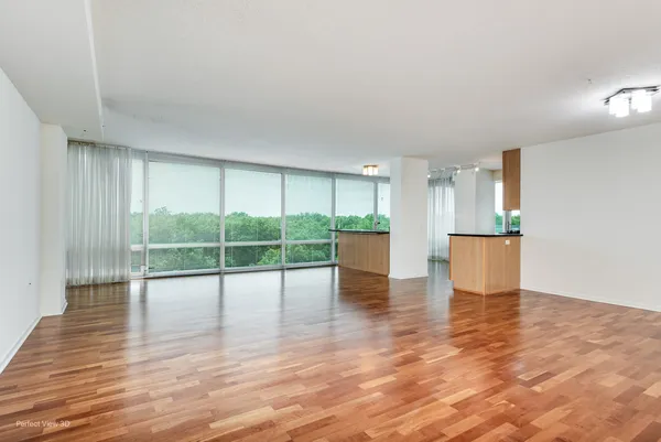 a view of empty room with wooden floor and floor to ceiling window