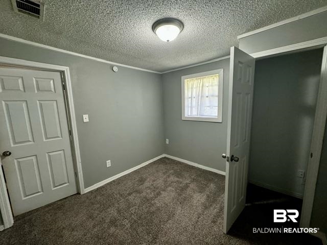 502 Forest Street Mobile, AL 36611 - Photo 6 of 10 Unfurnished bedroom featuring dark carpet and a textured ceiling