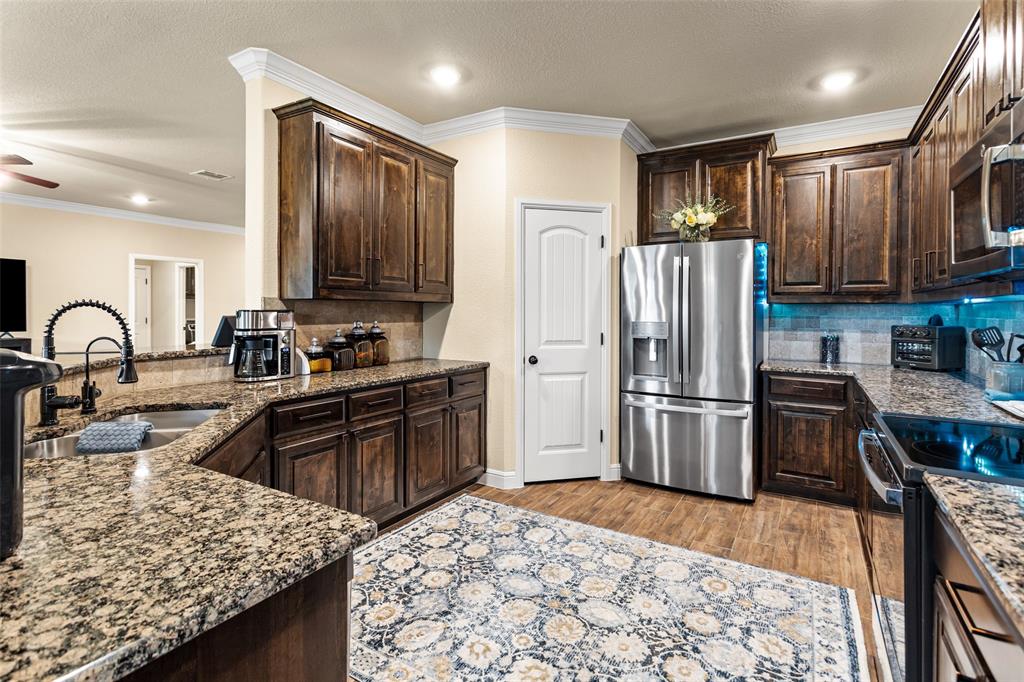 223 Cottongame Road Weatherford, TX 76088 - Photo 12 of 35 a kitchen with granite countertop wooden cabinets a refrigerator and a stove top oven
