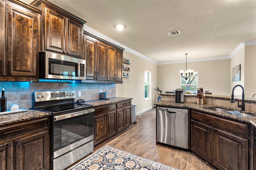 223 Cottongame Road Weatherford, TX 76088 - Photo 13 of 35 a kitchen with stainless steel appliances granite countertop a sink stove and microwave