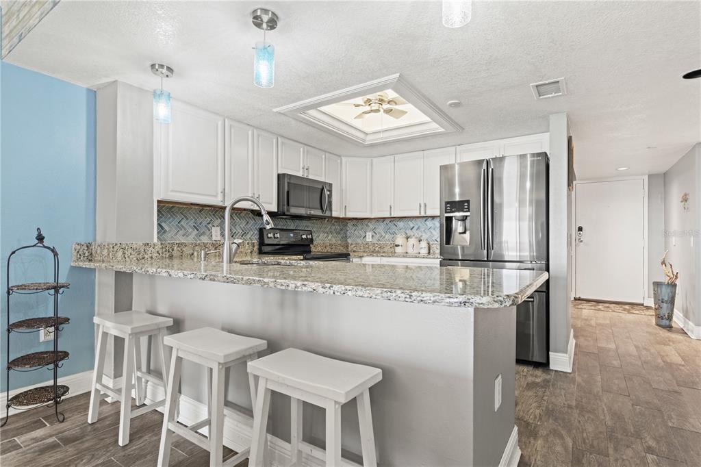 6035 Sea Ranch Drive, Unit 415 Hudson, FL 34667 - Photo 11 of 49 a kitchen with stainless steel appliances granite countertop a sink a stove a refrigerator cabinets and chairs