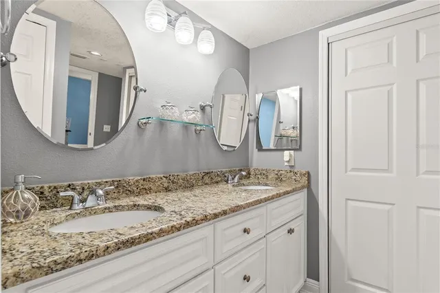 a bathroom with a granite countertop sink a mirror and a shower