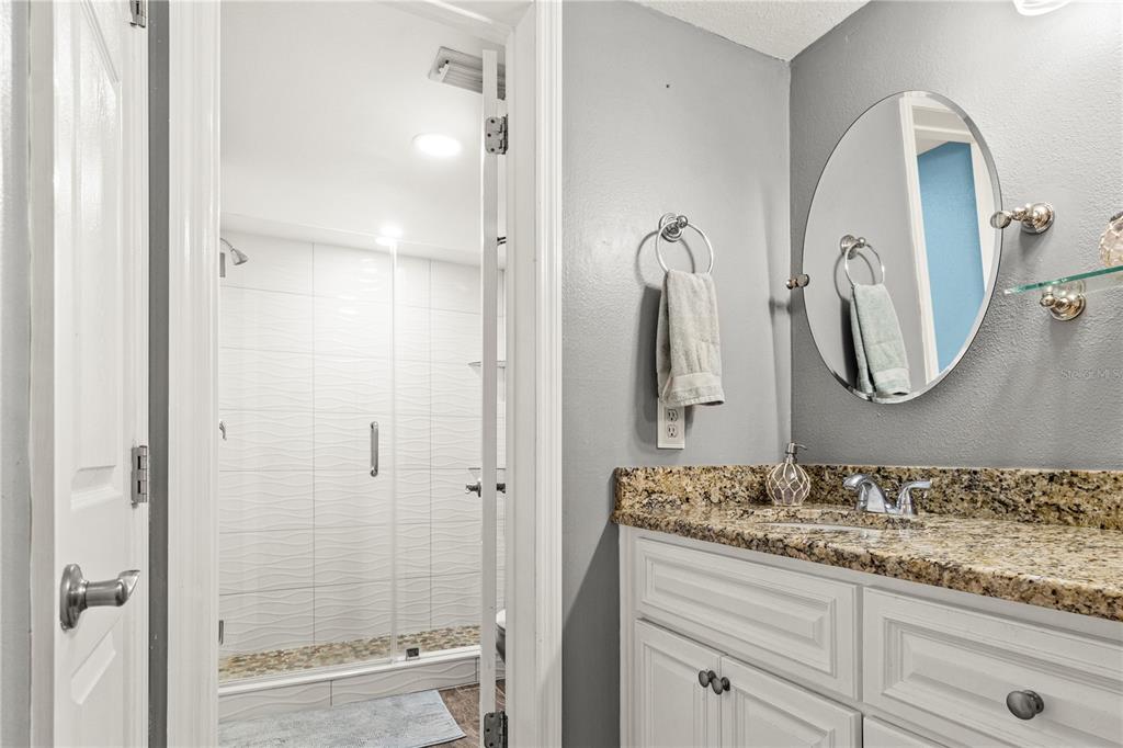 6035 Sea Ranch Drive, Unit 415 Hudson, FL 34667 - Photo 26 of 49 a bathroom with a granite countertop sink a mirror and a shower