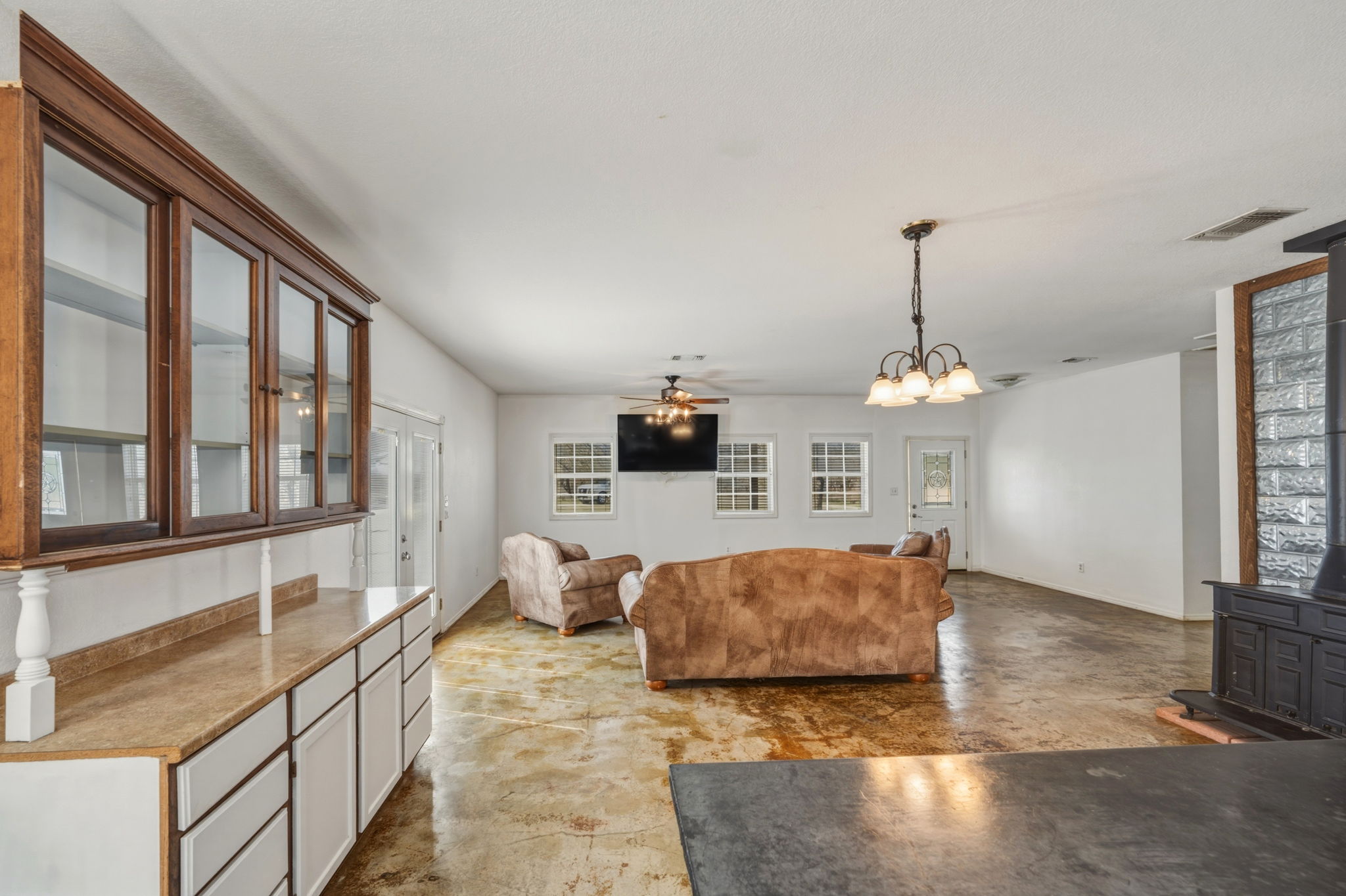 1301 Altwein Road Blanco, TX 78606 - Photo 16 of 40 Living area featuring concrete flooring, a wood stove, a ceiling fan, and suspended lighting