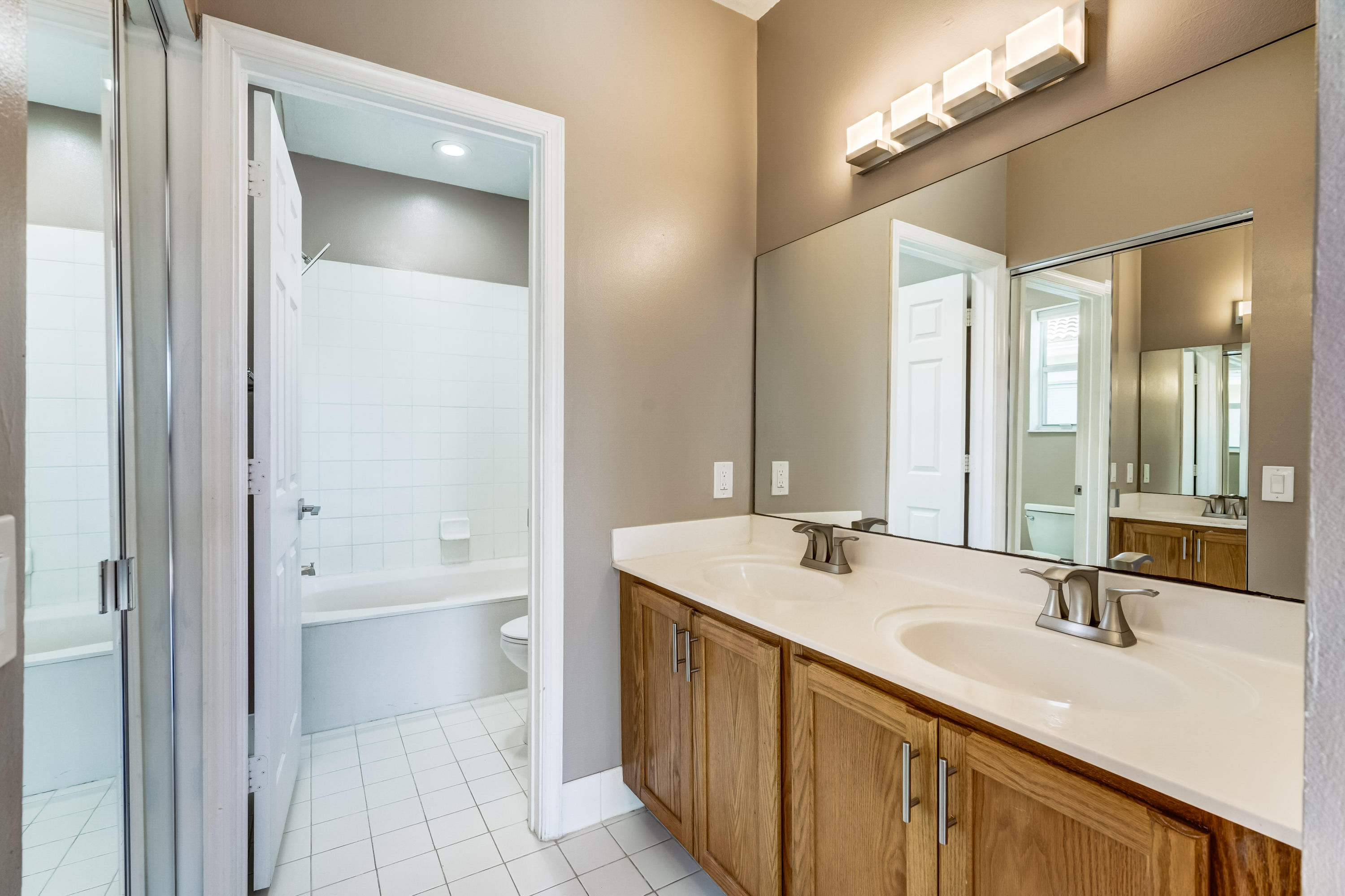 3174 Laurel Ridge Circle Riviera Beach, FL 33404 - Photo 5 of 32 a bathroom with a double vanity sink a mirror and a bathtub