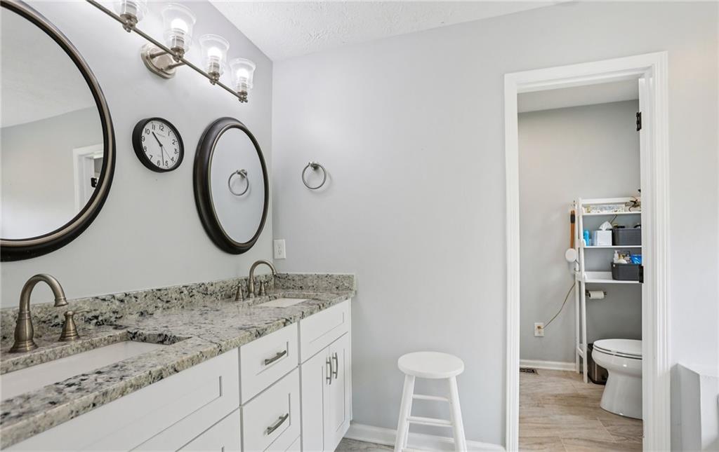 9725 Kings Road Gainesville, GA 30506 - Photo 15 of 32 a bathroom with a granite countertop toilet sink and mirror