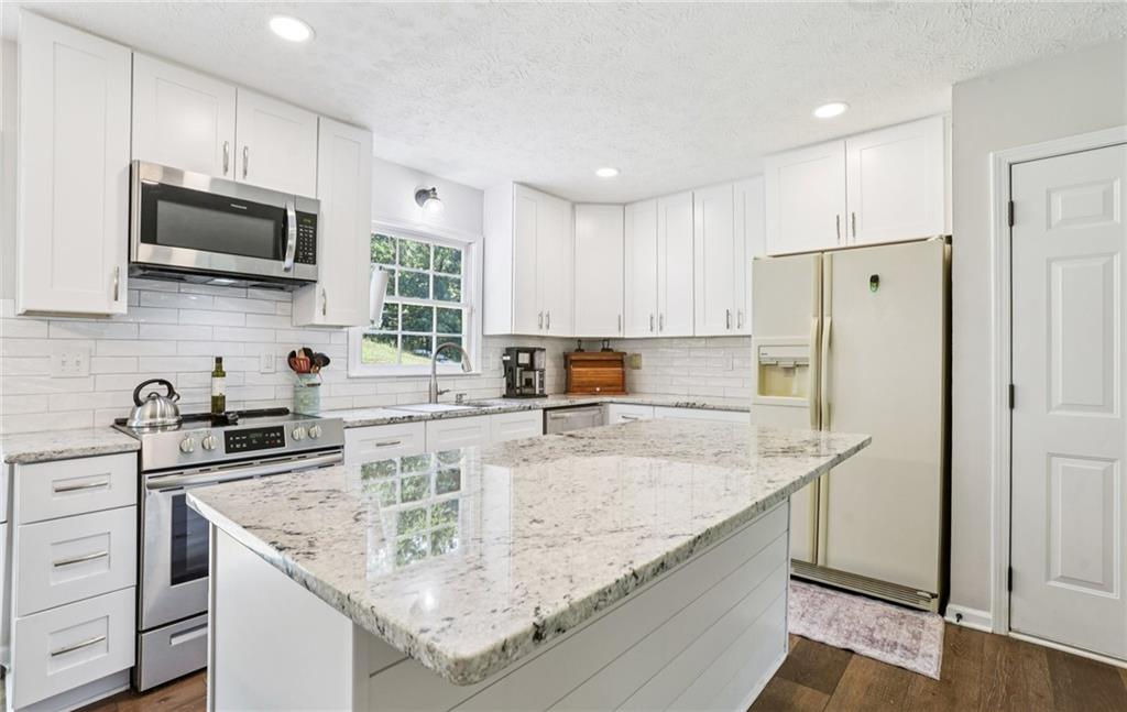 9725 Kings Road Gainesville, GA 30506 - Photo 27 of 32 a kitchen with stainless steel appliances granite countertop a sink stove and refrigerator