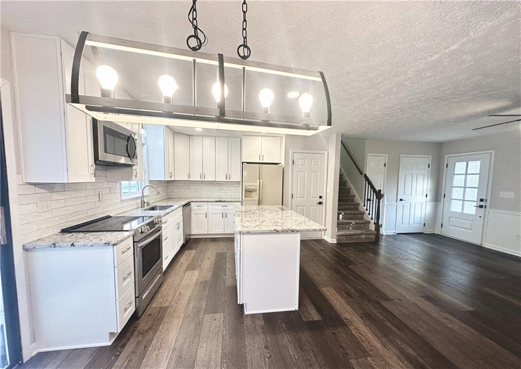 9725 Kings Road Gainesville, GA 30506 - Photo 8 of 32 an open kitchen with wooden floor and stainless steel appliances