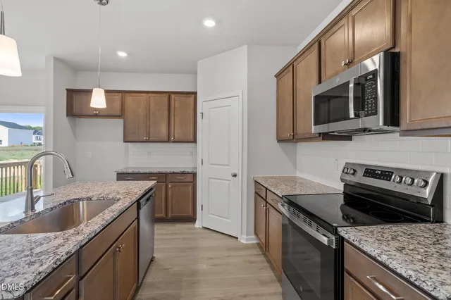 a kitchen with stainless steel appliances granite countertop a sink stove microwave and refrigerator