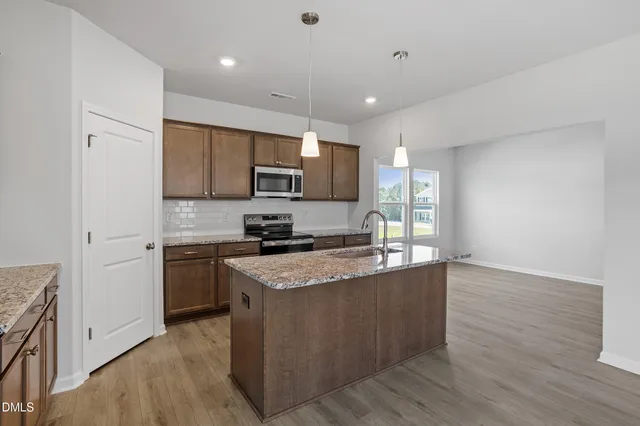a kitchen with stainless steel appliances granite countertop a stove a sink and a refrigerator