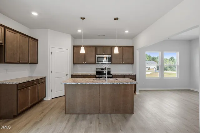 a large kitchen with stainless steel appliances granite countertop a stove a sink and a microwave