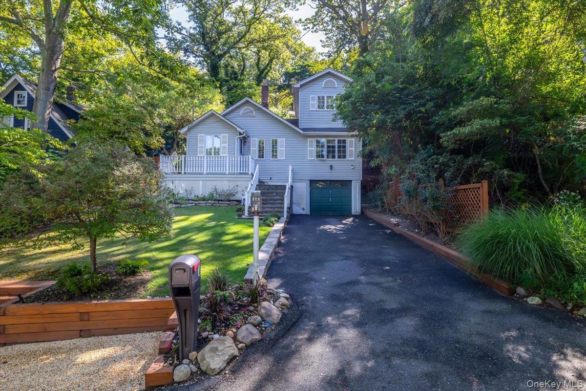 View of front of home featuring stairway to front door, asphalt driveway, a front yard, and an attached garage