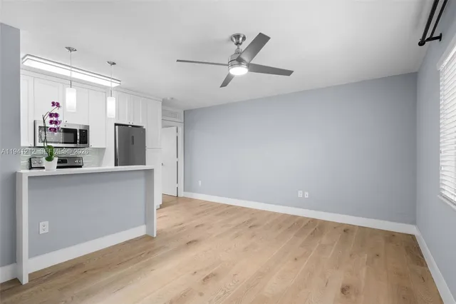 a view of a kitchen with refrigerator and wooden floor