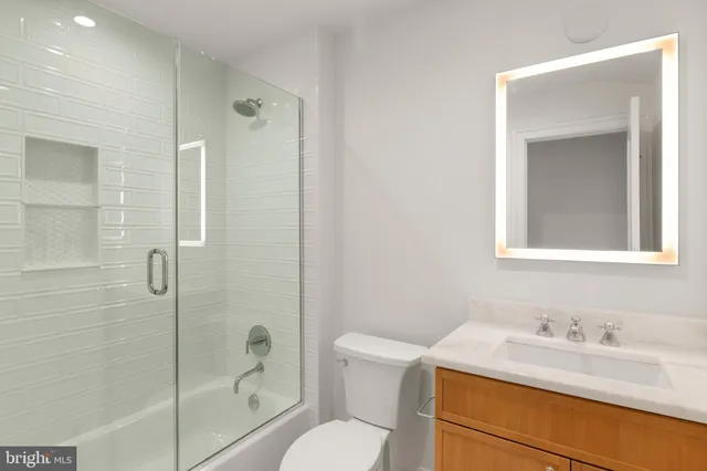 a bathroom with a granite countertop sink toilet a mirror and shower
