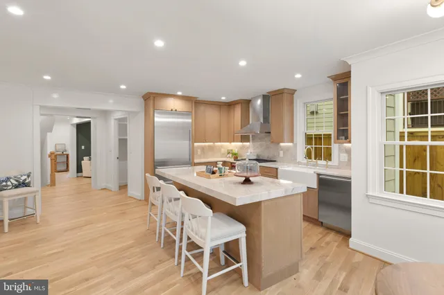 a kitchen with stainless steel appliances a dining table chairs and wooden floor