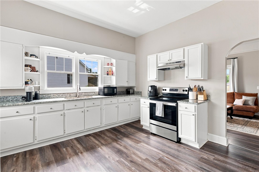 7 McCaughrin Street Pelzer, SC 29669 - Photo 21 of 24 A well-equipped kitchen features white cabinetry and sleek stainless steel appliances, flowing into an inviting living space.