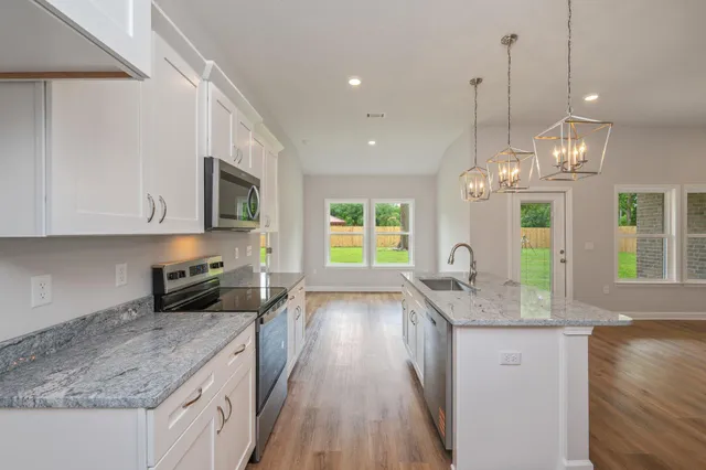 a kitchen with granite countertop a stove oven and a sink with cabinets