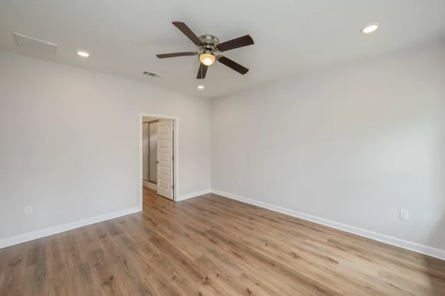 an empty room with wooden floor a ceiling fan and a window