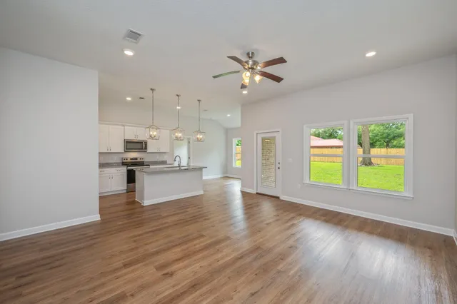 a view of an empty room with a window and wooden floor