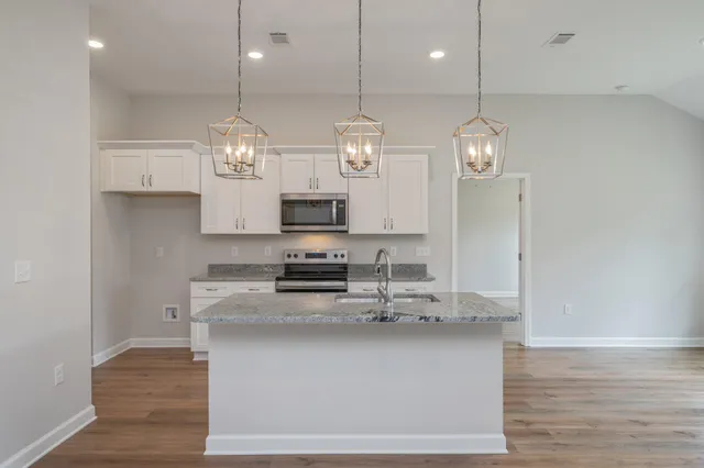 a kitchen with stainless steel appliances granite countertop a sink a stove top oven a counter space and cabinets