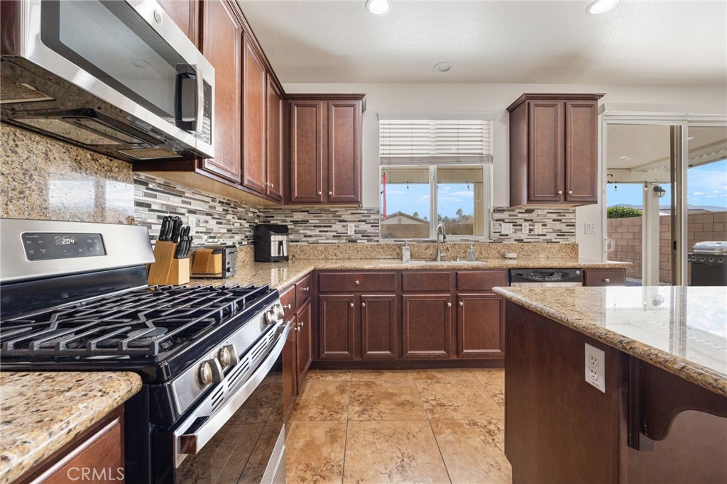 84155 Tramonto Way Indio, CA 92203 - Photo 18 of 38 a kitchen with stainless steel appliances granite countertop a sink stove and cabinets