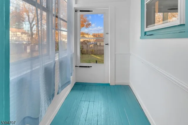 a view of a hallway with wooden floor and a bathroom