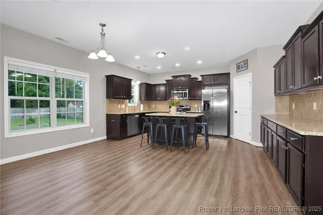 a open kitchen with kitchen island wooden floors stainless steel appliances and a window