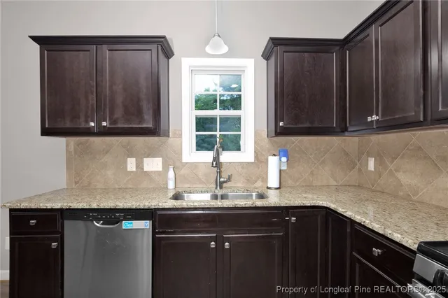 a kitchen with granite countertop wooden cabinets a sink and dishwasher