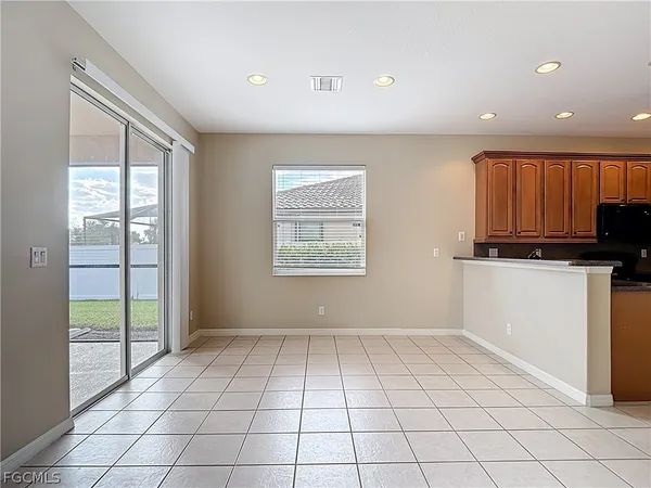 a view of an empty room with kitchen and window